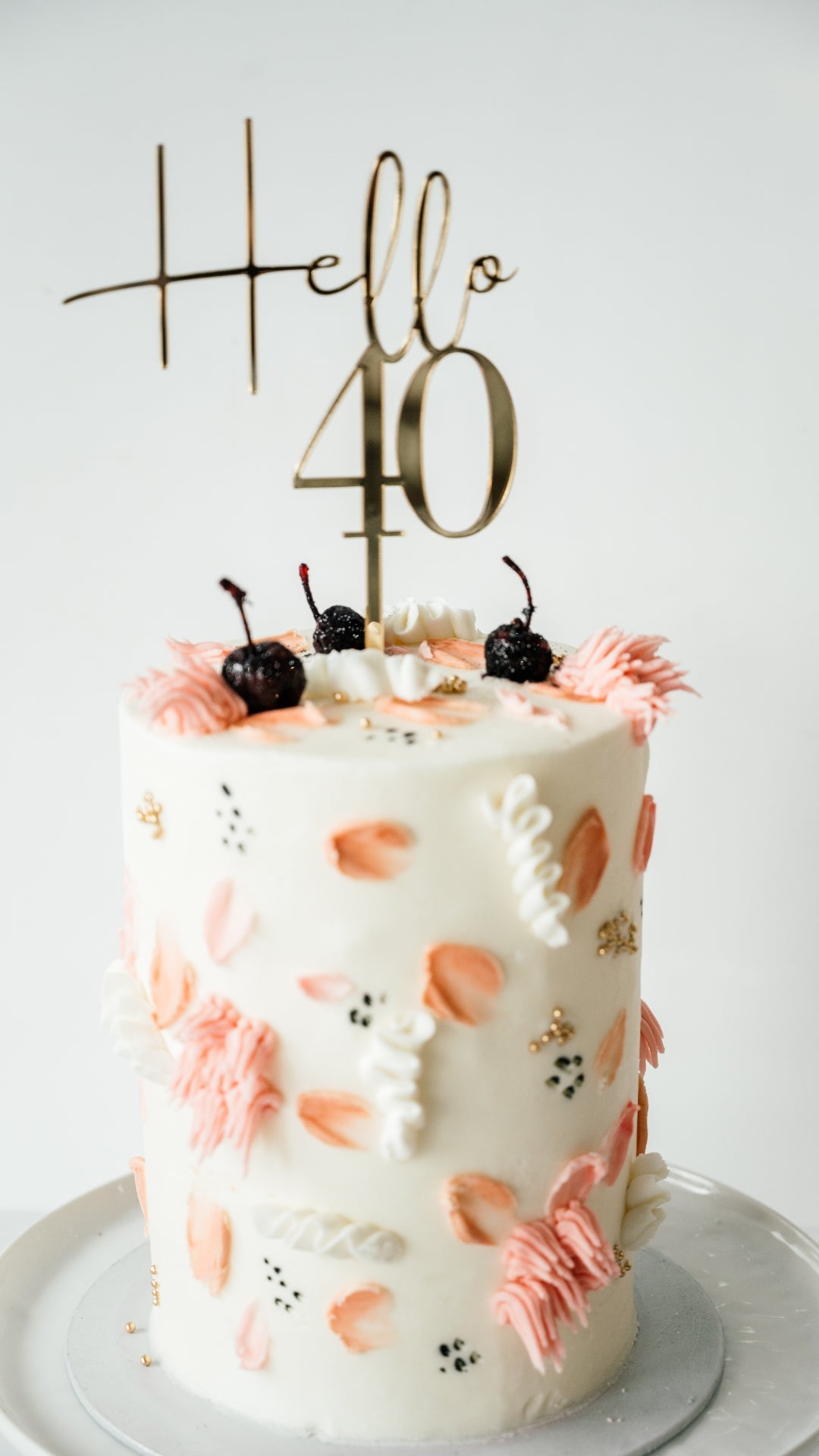 Decorative cake with floral patterns and 'Hello 40' topper on a white background