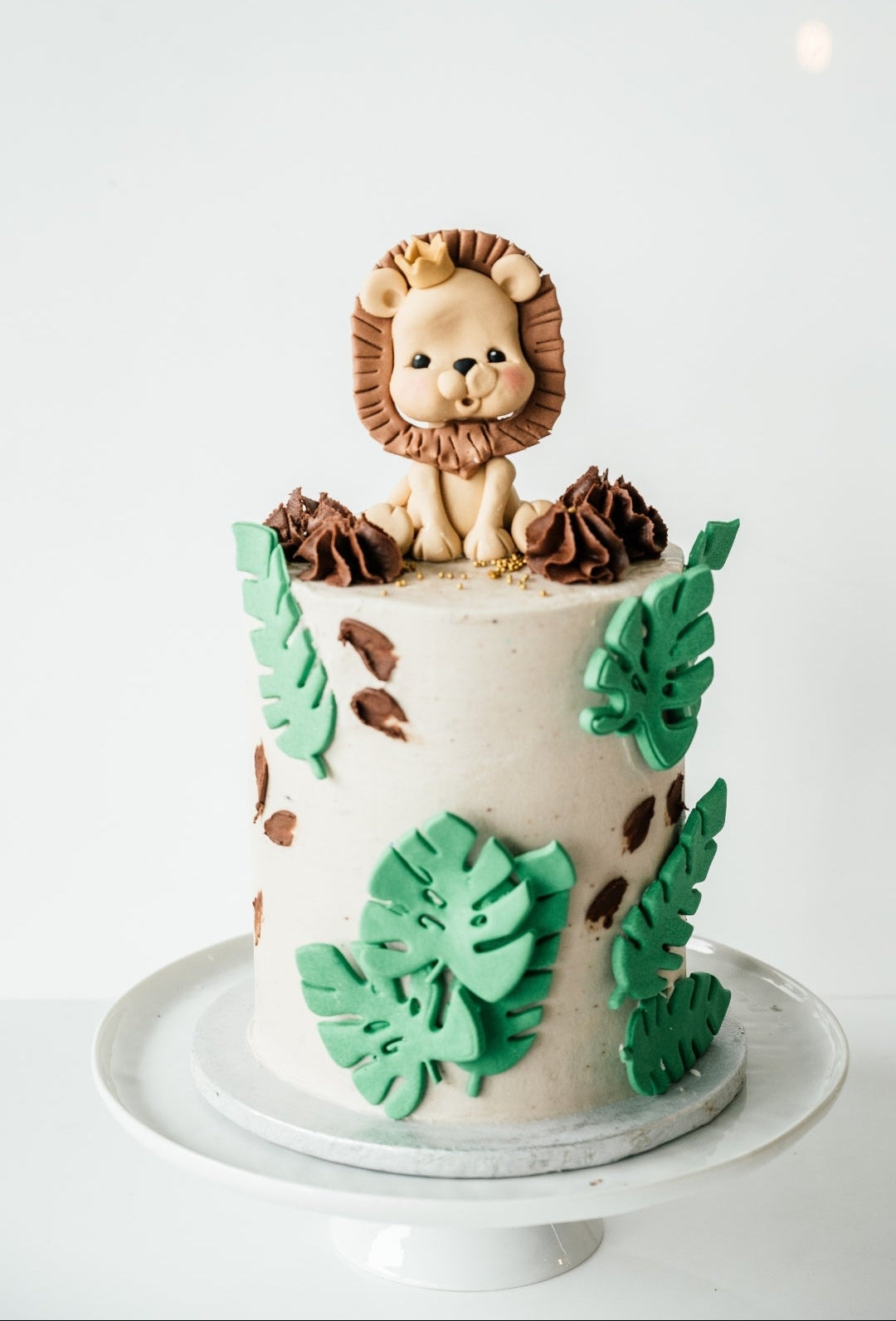 Cake with lion figurine and leaf decorations on a white background