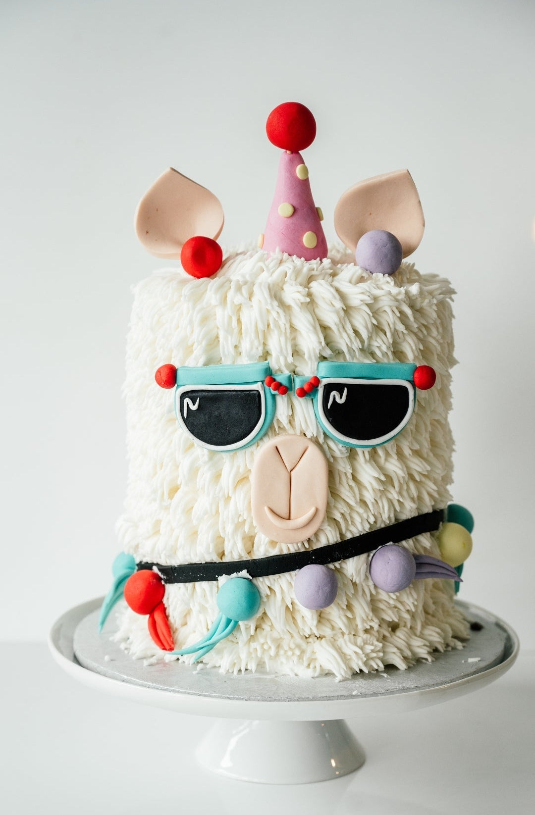 Cake decorated like a llama with colorful accessories 